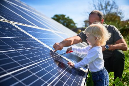 Ein Mann zeigt seinem kleinen Kind an einem sonnigen Tag die Solarpaneele. Der Vater präsentiert seinem Sohn moderne Technologie.